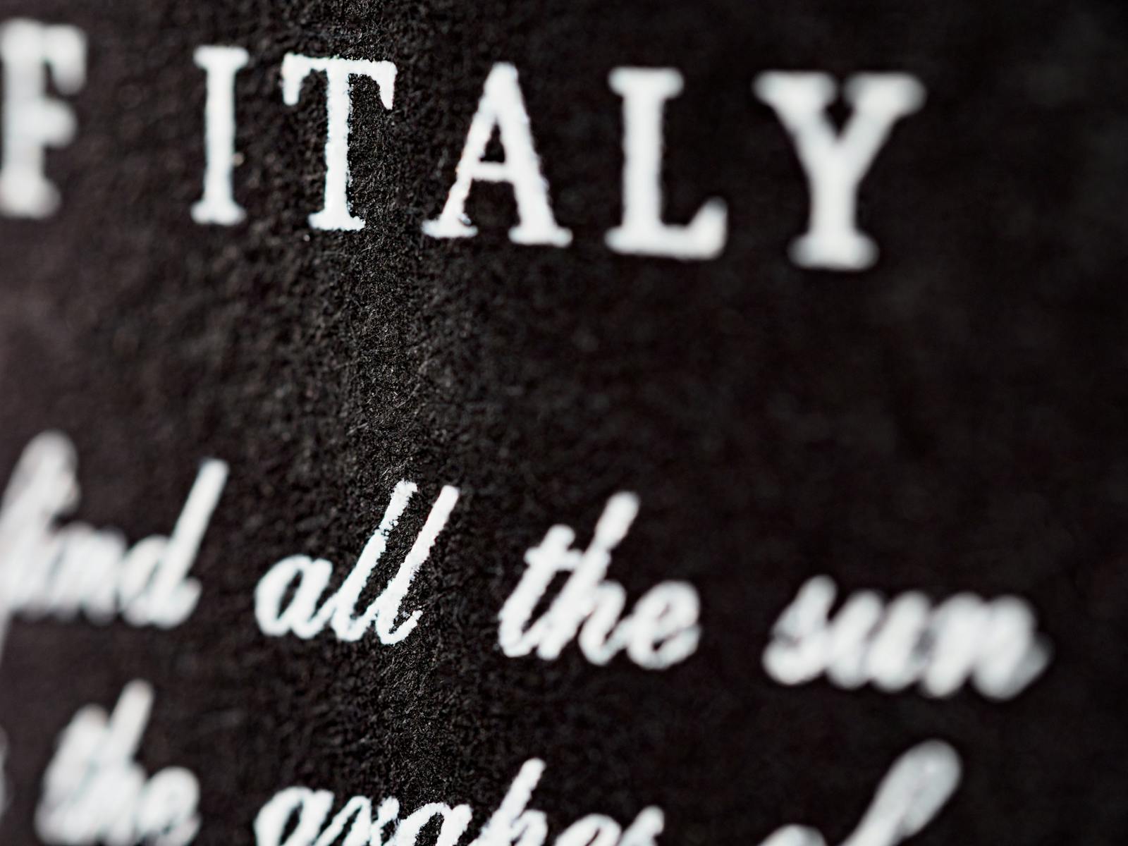 Detailed close-up of textured black surface with white typography 'ITALY.'