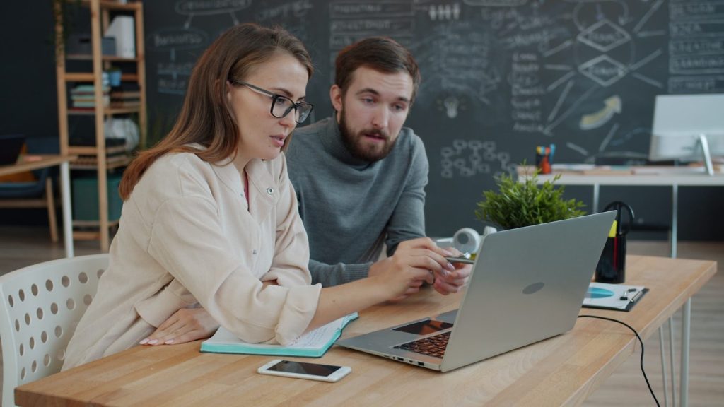 Two colleagues collaborating on a project at a laptop.