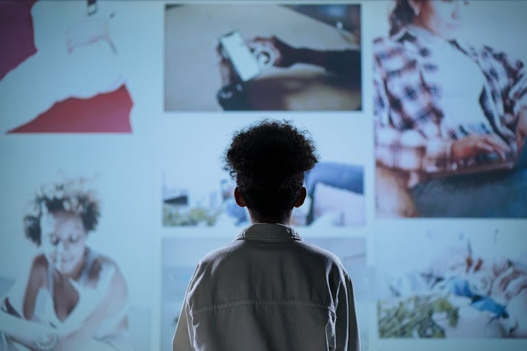 A child stands in front of a digital display showcasing various lifestyle images.