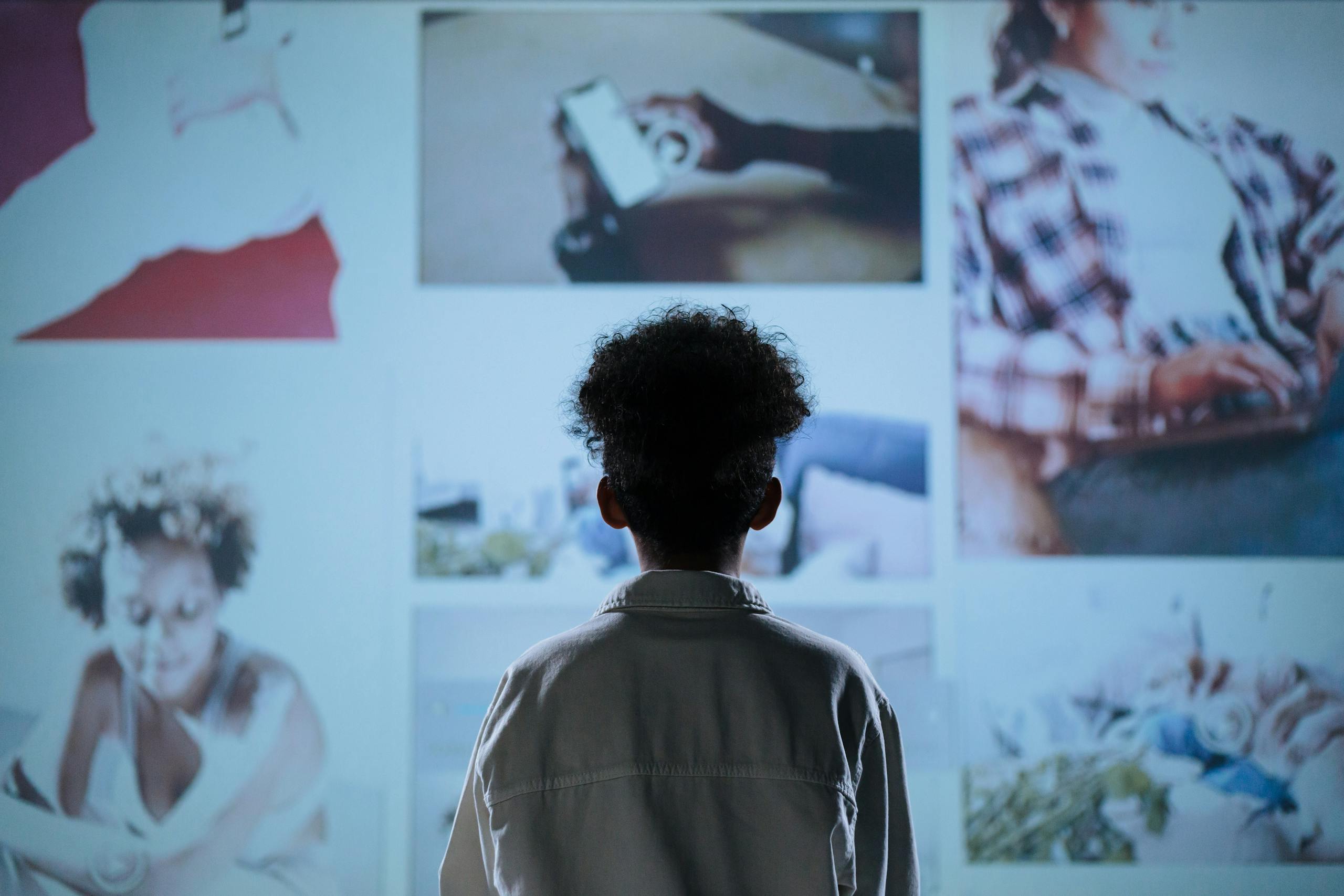 A child stands in front of a digital display showcasing various lifestyle images.