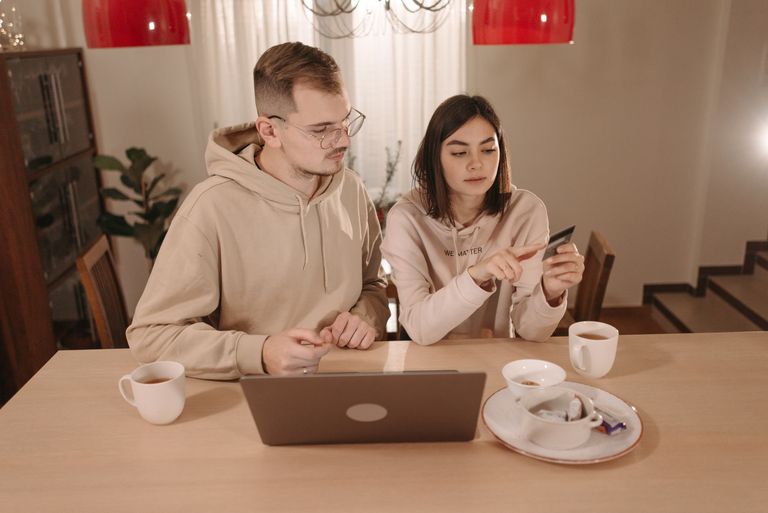 A couple enjoying online shopping with a laptop and credit card at home. Cozy indoor setting.