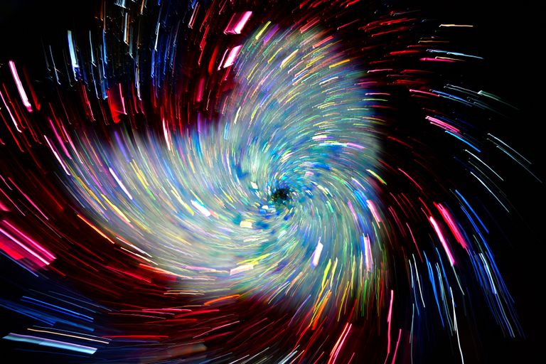 Vivid spiral of colorful light trails creating a dynamic abstract pattern.