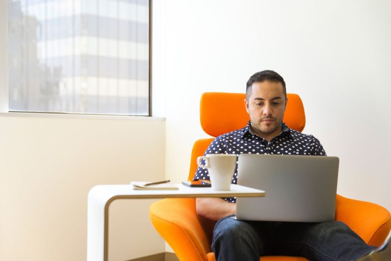 Man focused on working at desk with laptop in a contemporary office setting.