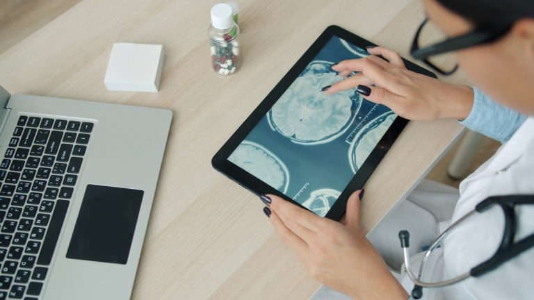 Doctor examining brain scan on tablet at desk