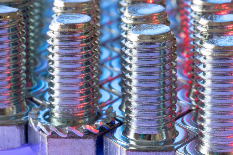 Detailed view of shiny metal screws with colorful reflections and selective focus.