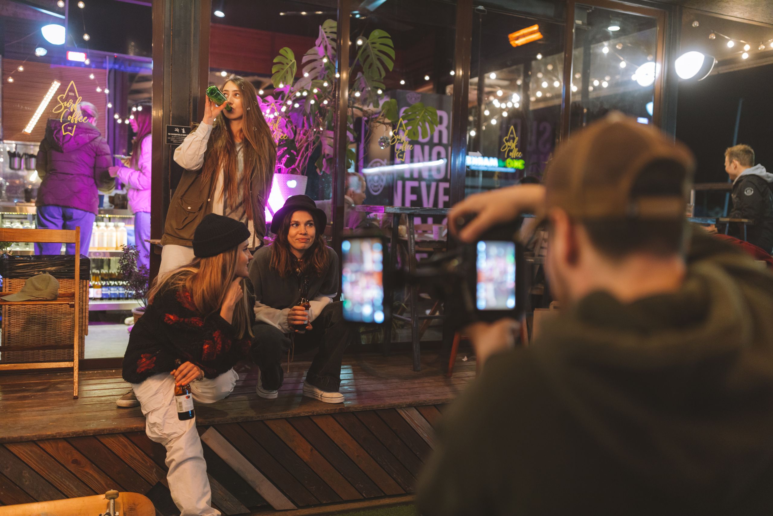 Group of friends enjoying nightlife, wearing trendy streetwear, captured candidly outside a bar.