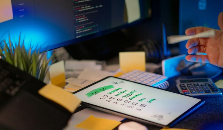 Developer working on multiple screens in a dark office