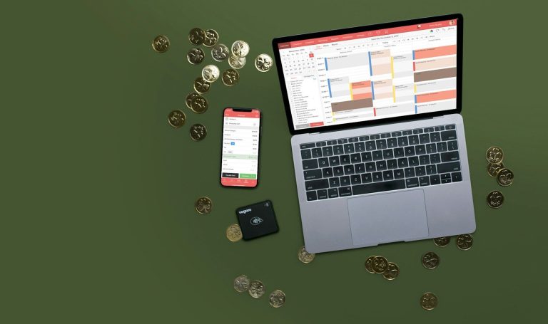 Laptop, phone, and coins on a green surface