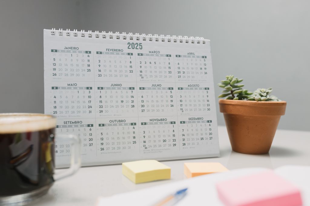 A 2025 desk calendar with coffee, sticky notes, and succulents for planning.