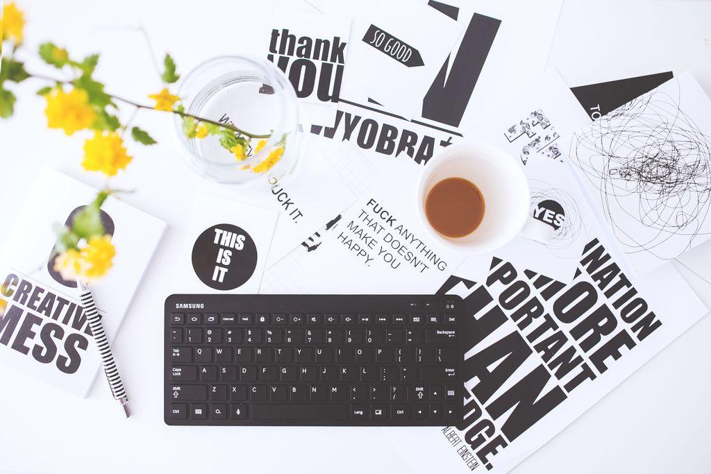 Overhead view of a creative workspace with scattered papers, coffee cup, and keyboard.