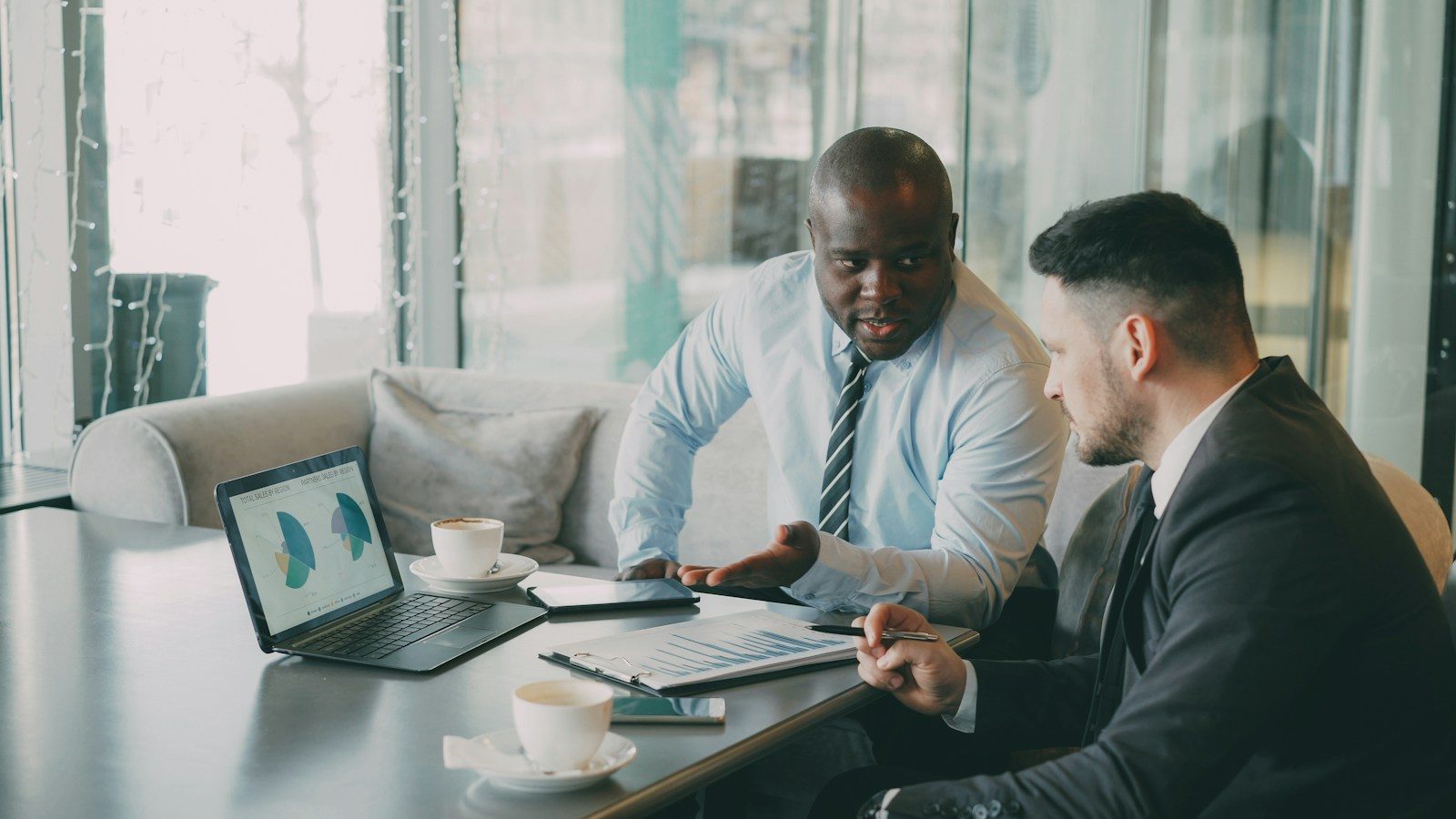 Two businessmen discussing charts on a laptop