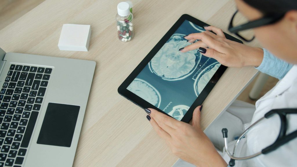 Doctor examining brain scan on tablet at desk